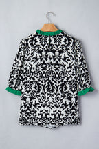 Back view of a black and white patterned ruffled blouse with green accents from LuckeLadybug LLC