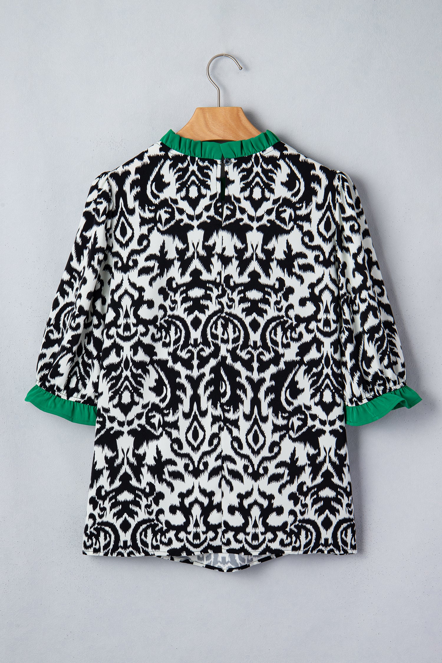Back view of a black and white patterned ruffled blouse with green accents from LuckeLadybug LLC