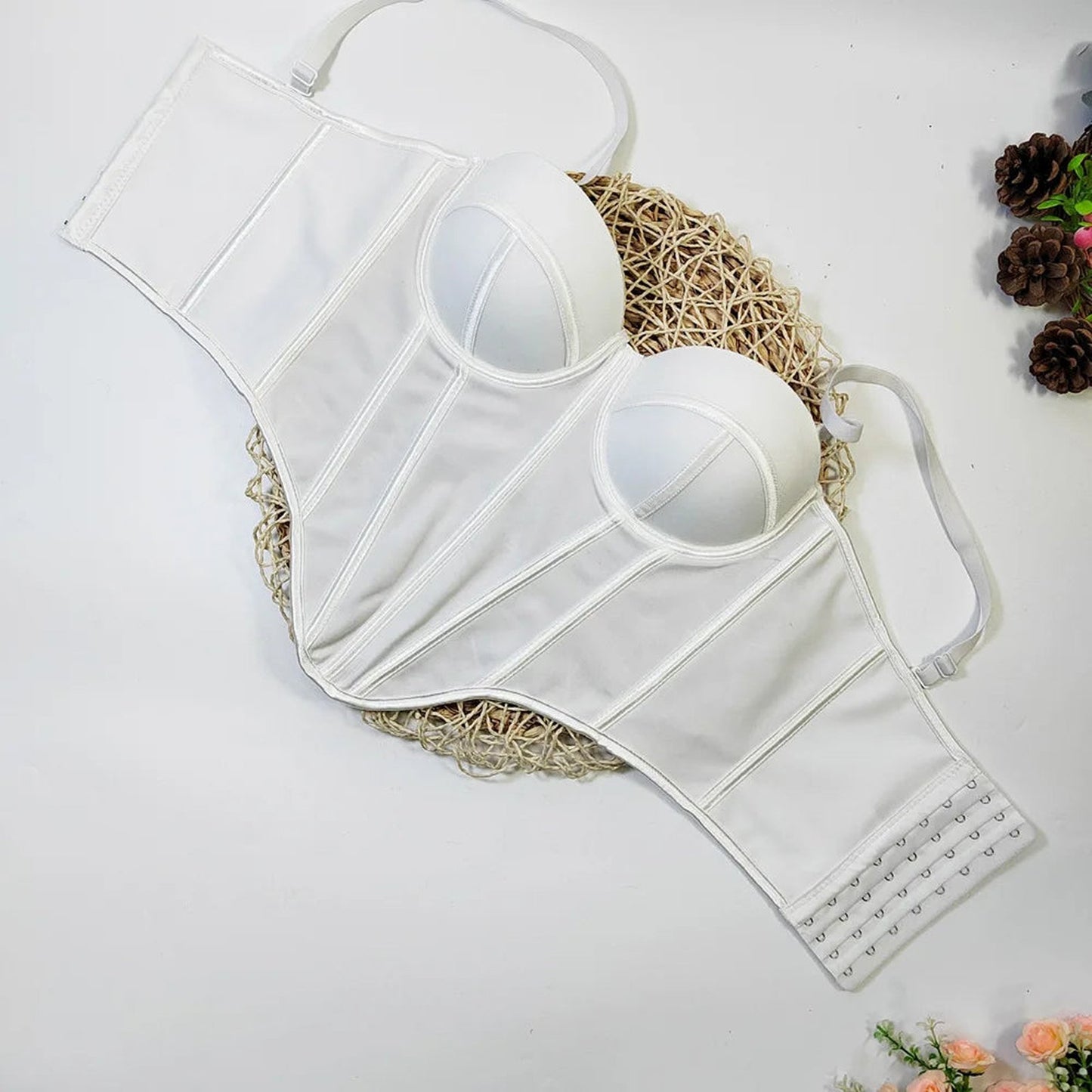 White lingerie with structured design, showcasing a sexy red corset top for women lay flat on a decorative mat