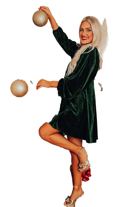 LuckeLadybug model posing in black velvet babydoll dress by decorated Christmas tree wearing metallic heels