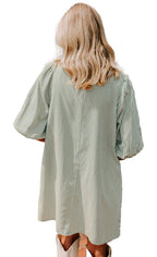 LuckeLadybug back view of model wearing green puff sleeve button down dress striped mini dress outdoors