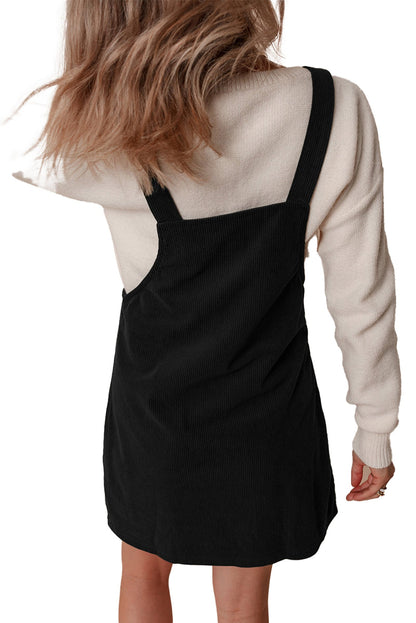 Back view of black corduroy mini overall dress by LuckeLadybug variant of vineyard green corduroy overall dress