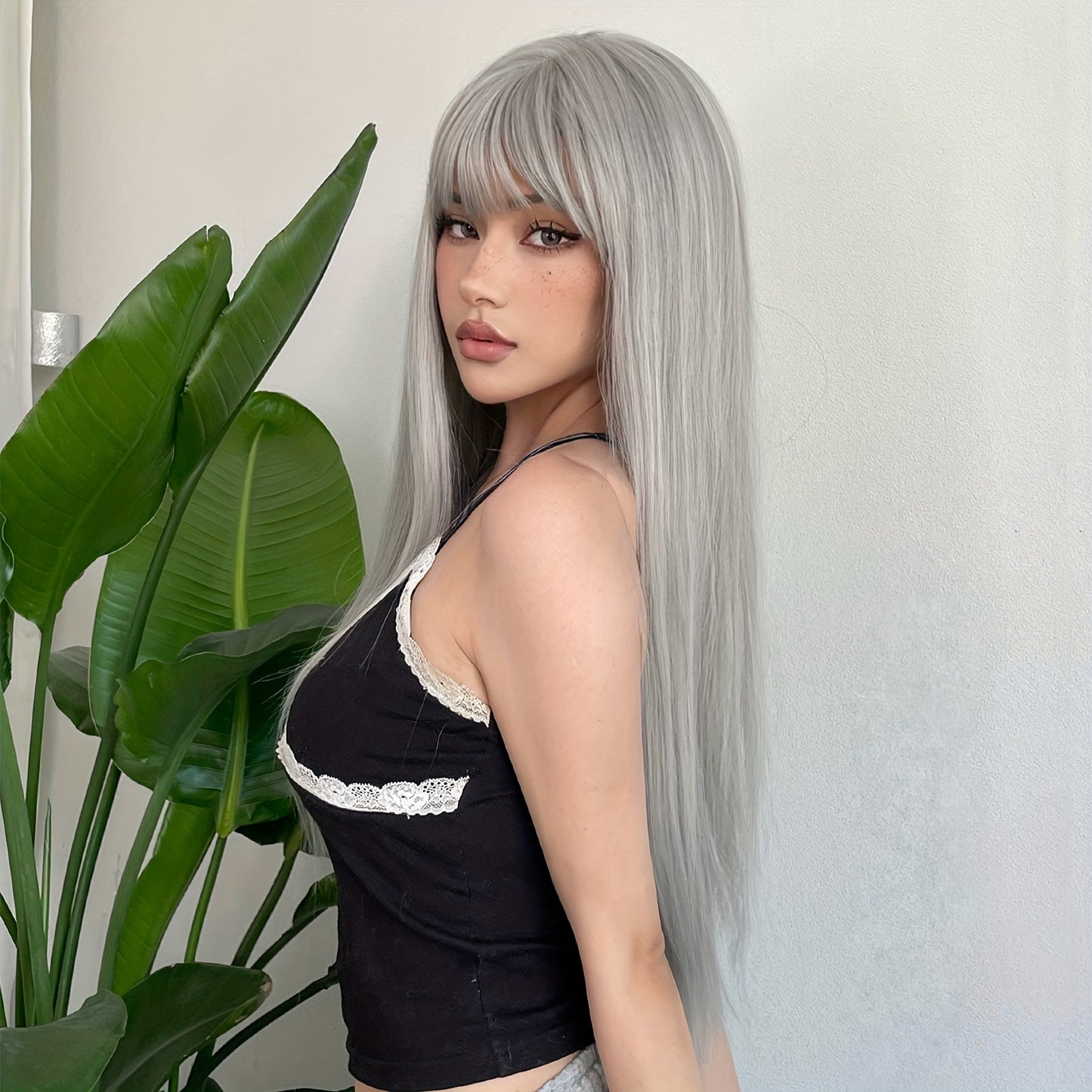 LuckeLadybug LLC silvery grey long straight wig styled with a center part against a green plant background