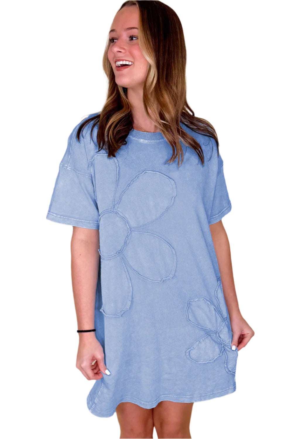 Woman wearing a sky blue t shirt dress with large floral embroidery by LuckeLadybug LLC