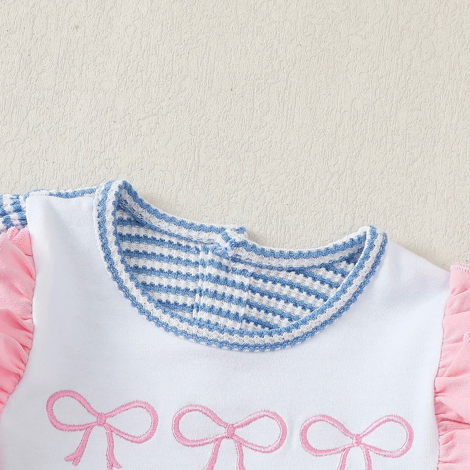 Striped long sleeve baby bodysuit with pink ruffle sleeves and decorative bows for infants