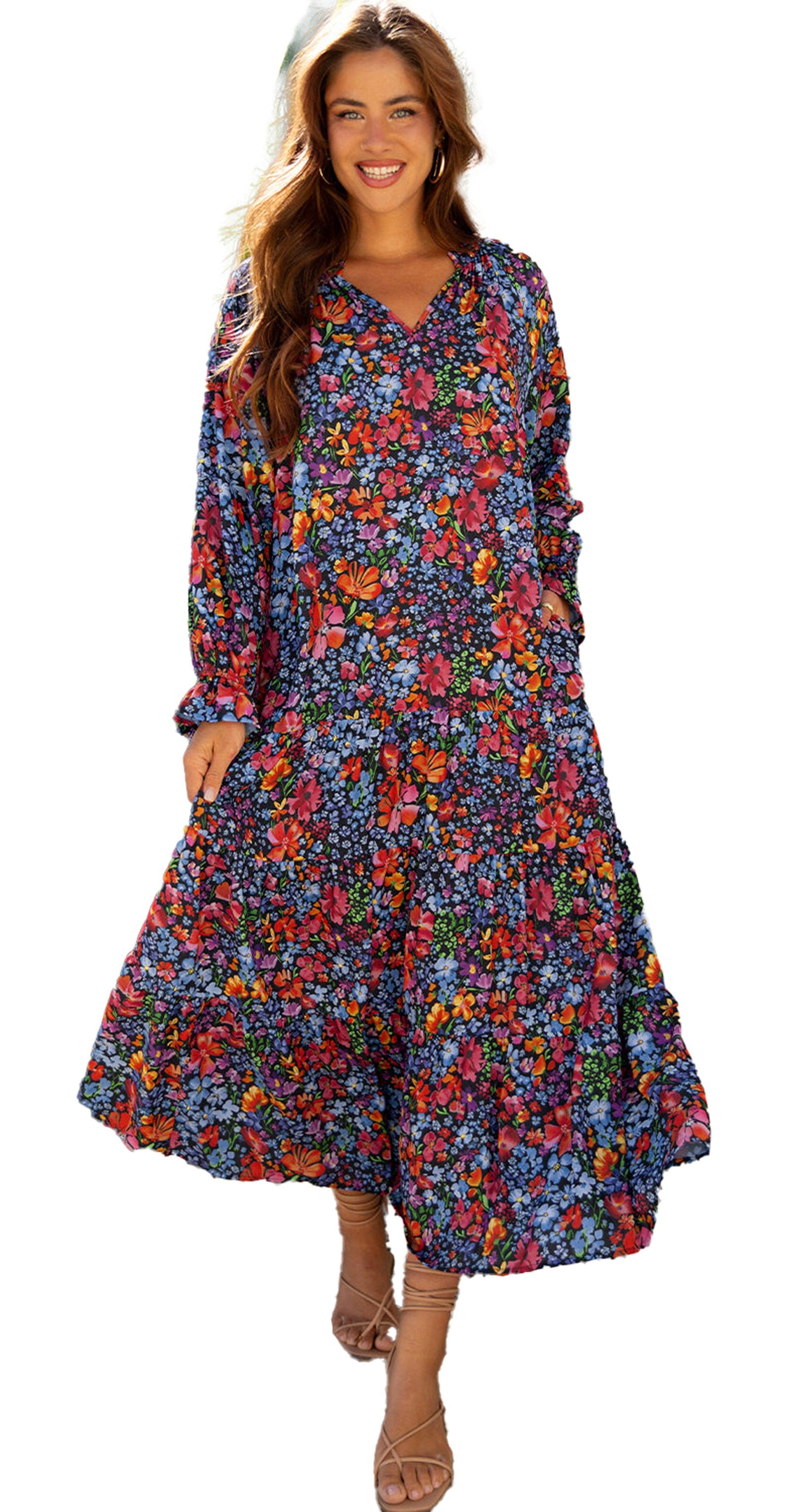 Model wearing a blue floral maxi dress with tassel tie long sleeves tiered skirt and strappy sandals