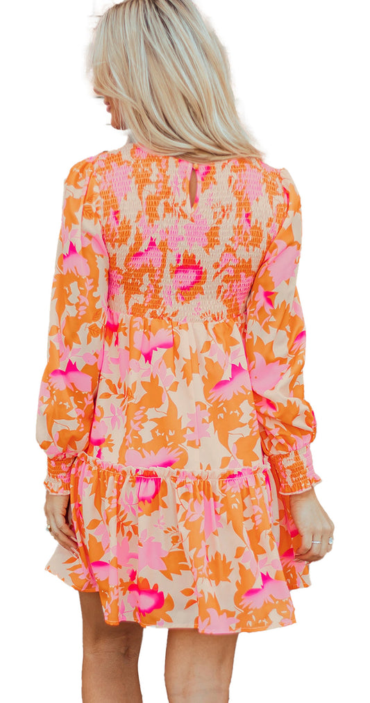 Back view of model wearing LuckeLadybug orange abstract print mini dress with smocked back and ruffle hem