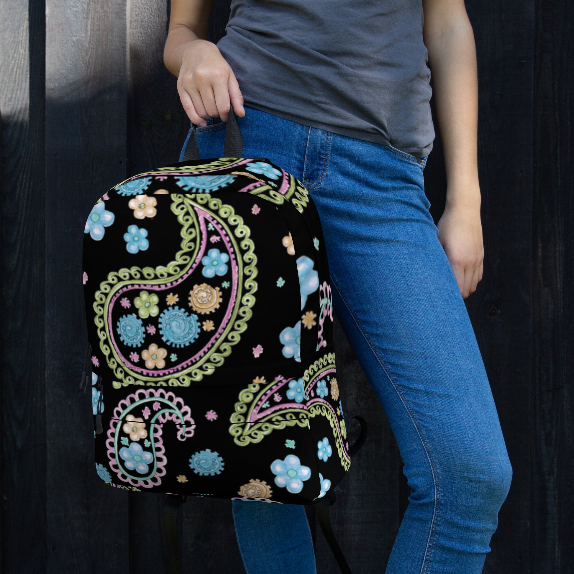 LuckeLadybug trendy paisley print backpack in black with multicolor floral design held by person in blue jeans