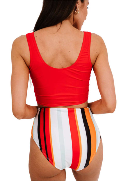Back view of trendy two-piece bathing suit with red top and colorful striped high-waisted bottoms