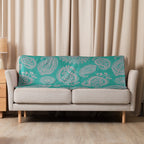 Turquoise paisley sherpa blanket draped over beige sofa in cozy living room setting