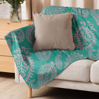 LuckeLadybug turquoise paisley sherpa blanket draped over beige couch with gray throw pillow