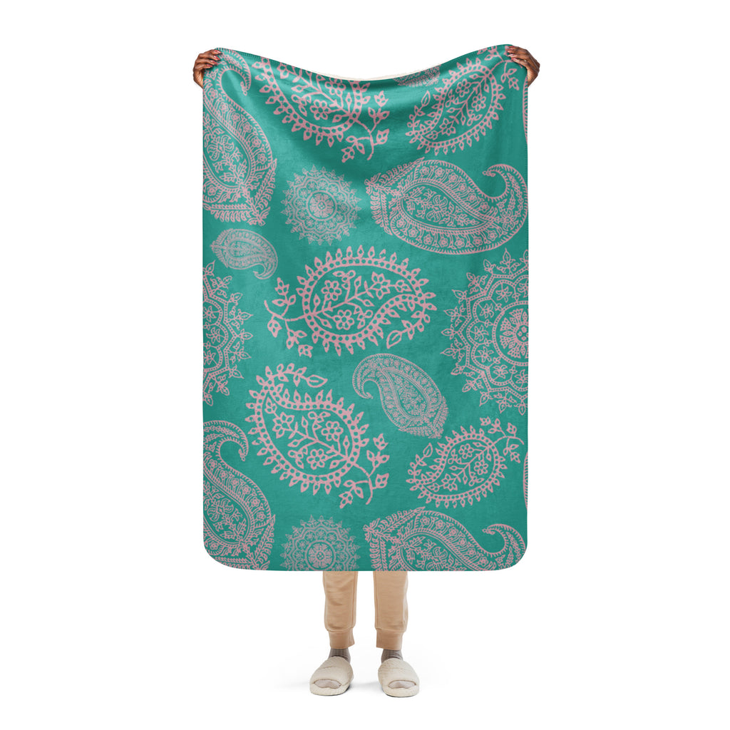 Turquoise paisley sherpa blanket held by person showcasing soft and cozy fabric