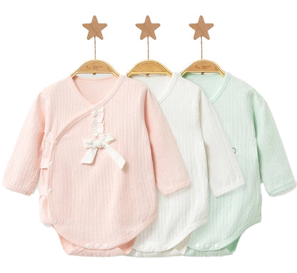 Set of three unisex baby cotton rompers in pink, white, and mint with snap closures and bow details