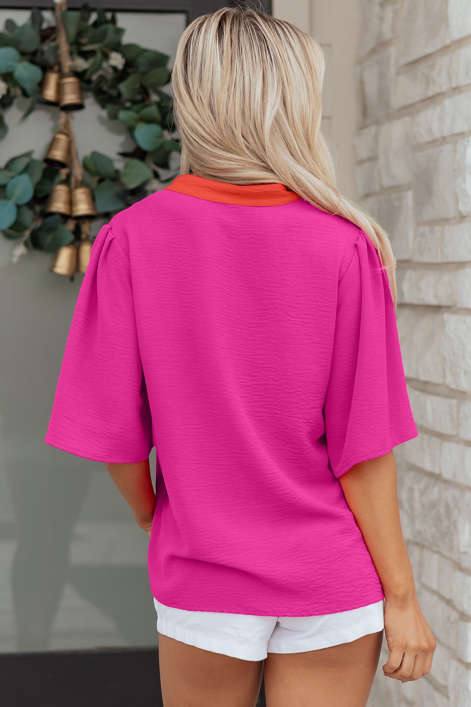 Back view of a vibrant pink v neck top by LuckeLadybug LLC with short sleeves