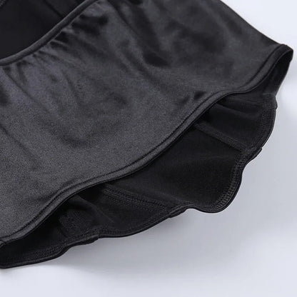 Black fabric detail of a red off shoulder corset top highlighting the ruffled hem and smooth texture