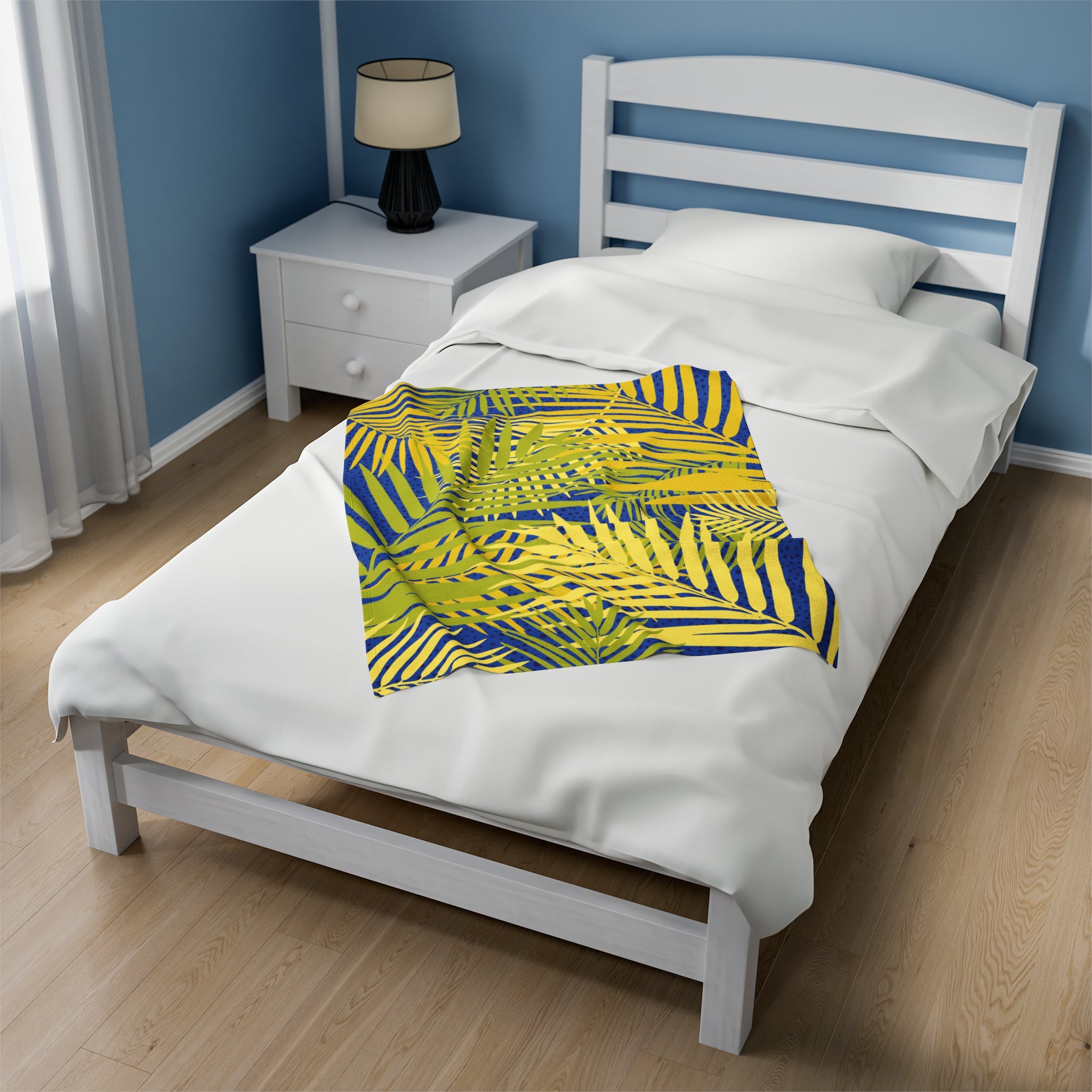 Tropical palm print blanket with yellow and blue leaf patterns on white bed in modern bedroom