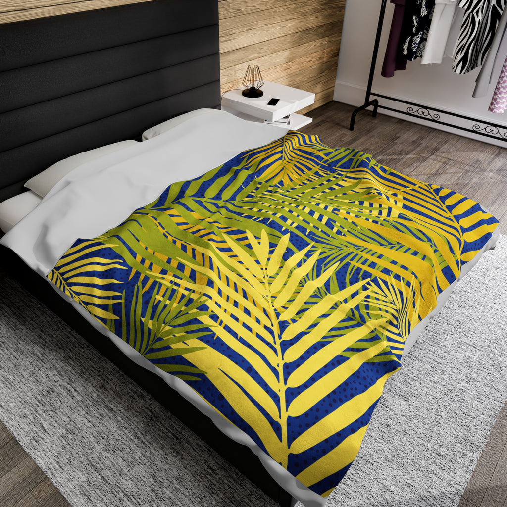 Tropical palm print blanket with yellow and blue palm leaves on bed in modern bedroom