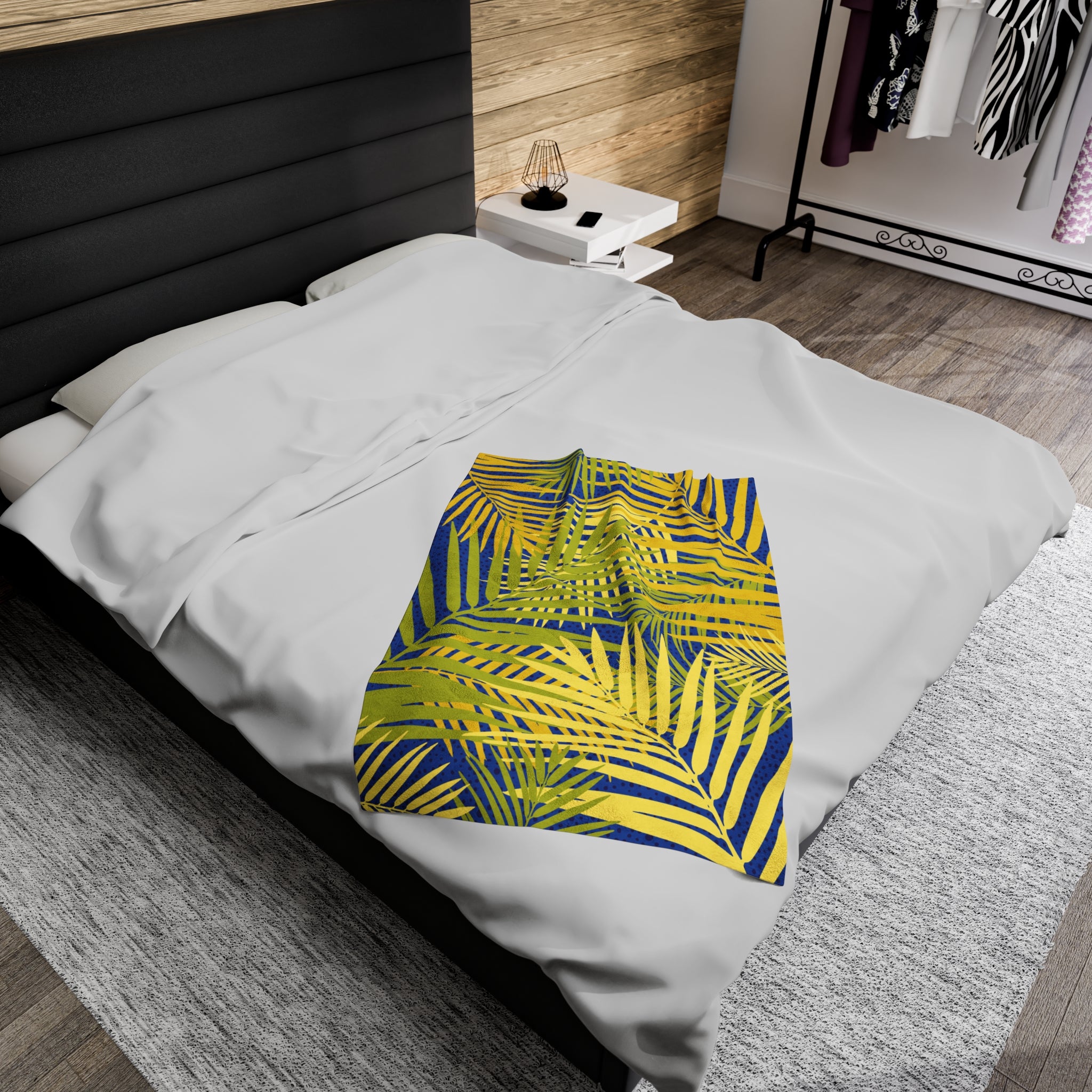 LuckeLadybug tropical palm print blanket with vibrant yellow and blue palm leaves on white bedding