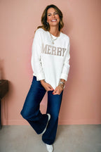 LuckeLadybug white MERRY Christmas sweater styled with wide-leg jeans and a cheerful smile