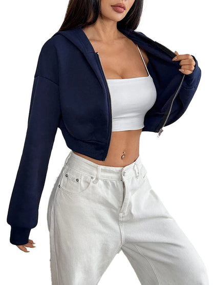 Women's cropped zip up hoodie in navy blue worn over a white tank top with white jeans