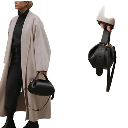 Stylish woman holding a black leather women's crossbody round bag with unique shape and modern design