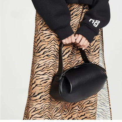 Stylish women's crossbody round bag in black, paired with a trendy outfit and animal print skirt