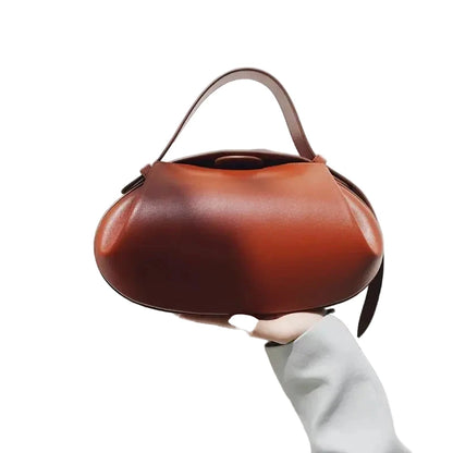 LuckeLadybug LLC women's crossbody round bag in brown held in one hand against a light background