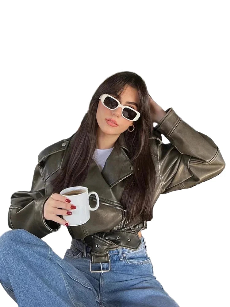 Stylish woman wearing a women's faux leather biker jacket with a coffee cup in a trendy cafe