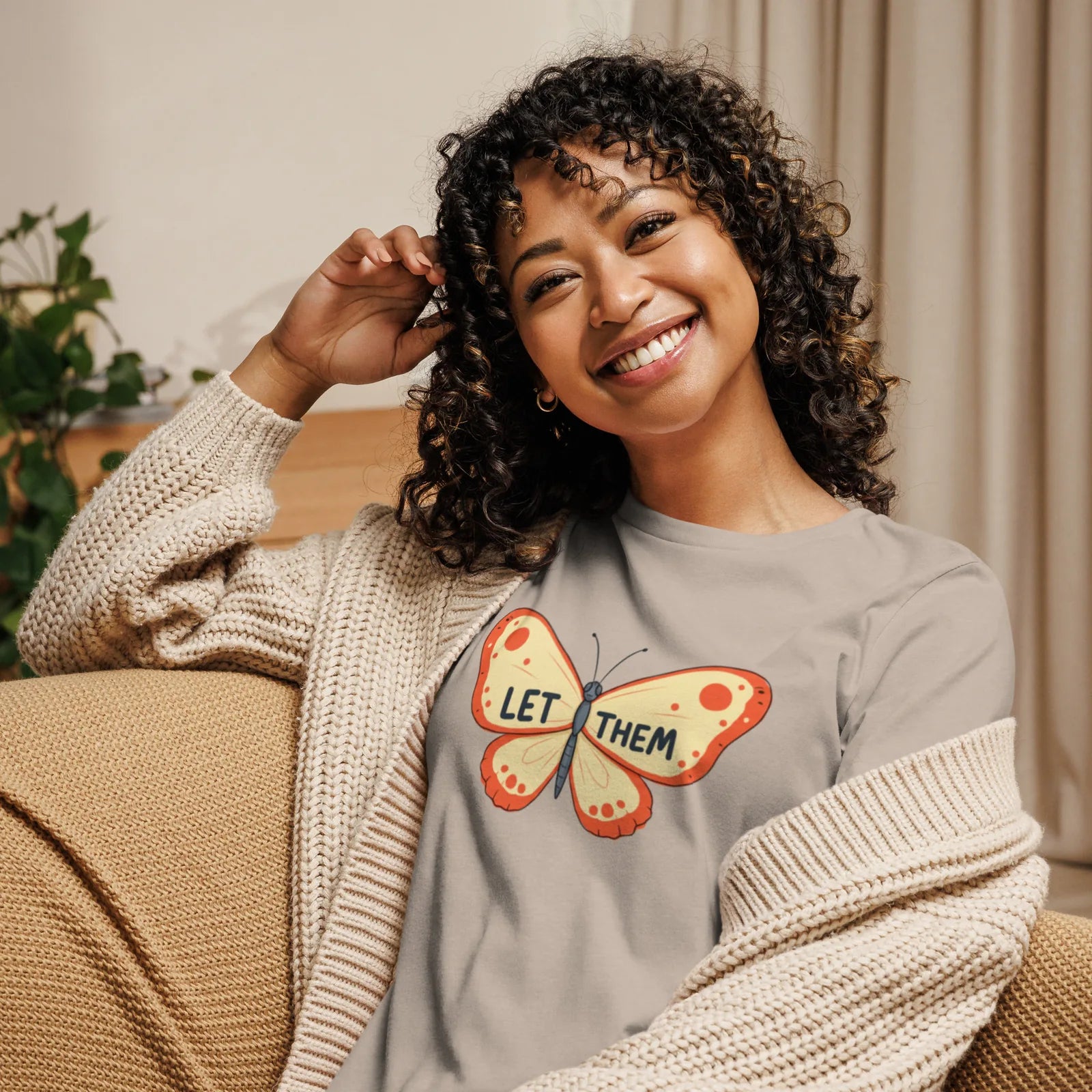 Woman wearing a gray sweatshirt with 'UR Underrated' text, sitting on a couch.