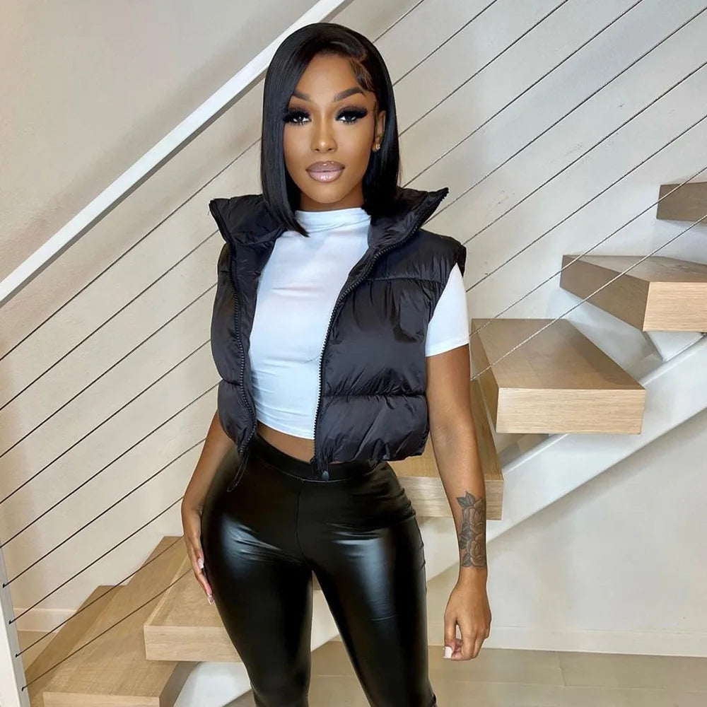 Trendy women's short down vest in black styled with a white crop top and leather pants