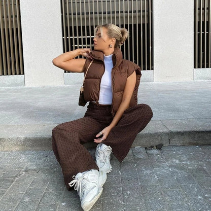 Trendy women's short down vest in brown, styled with high-waisted pants and sneakers for a chic look