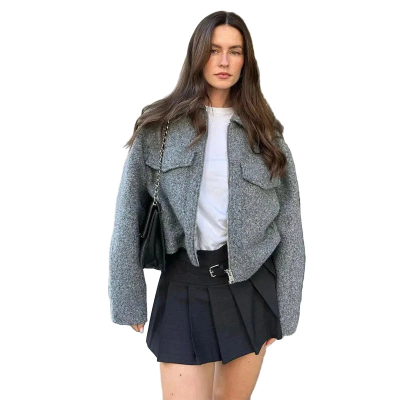 Stylish women's tweed cropped jacket in gray worn with a black pleated skirt