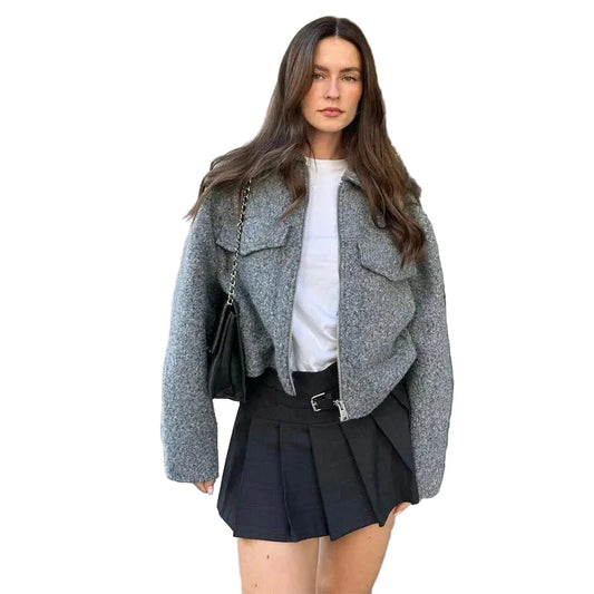 Stylish women's tweed cropped jacket in gray worn with a black pleated skirt