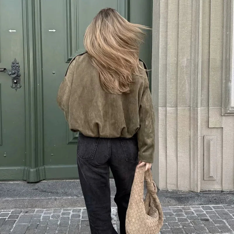 Woman wearing a women's vintage bomber jacket in olive green with casual black pants and a bag