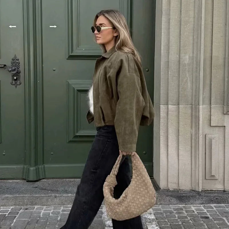 Woman wearing a women's vintage bomber jacket in olive green, paired with black pants and stylish sunglasses