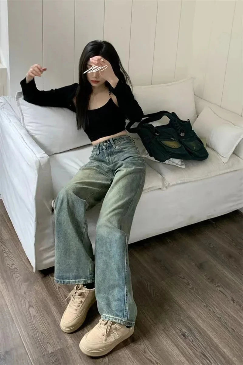 Fashionable y2k baggy jeans women styled with a cropped top and sneakers, sitting on a couch